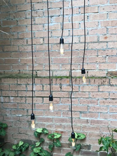 Pendant lights hanging by a brick wall