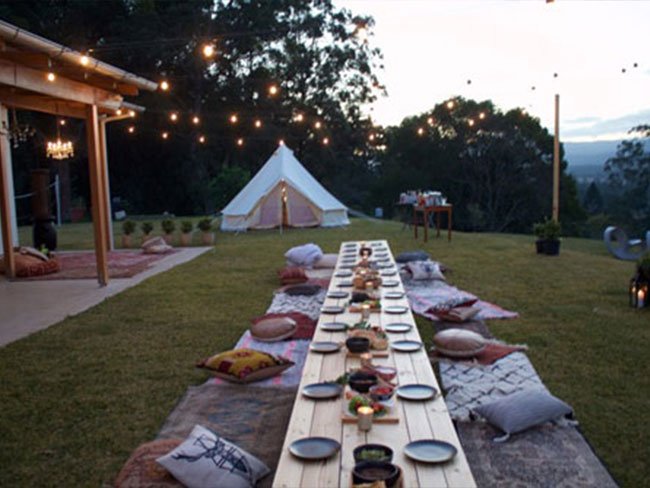 Festoon lights above large outdoor dining table