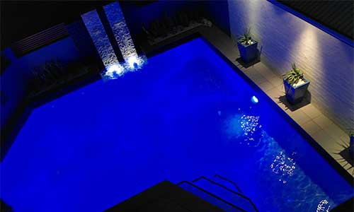 Outdoor pool with LED lights by waterfall